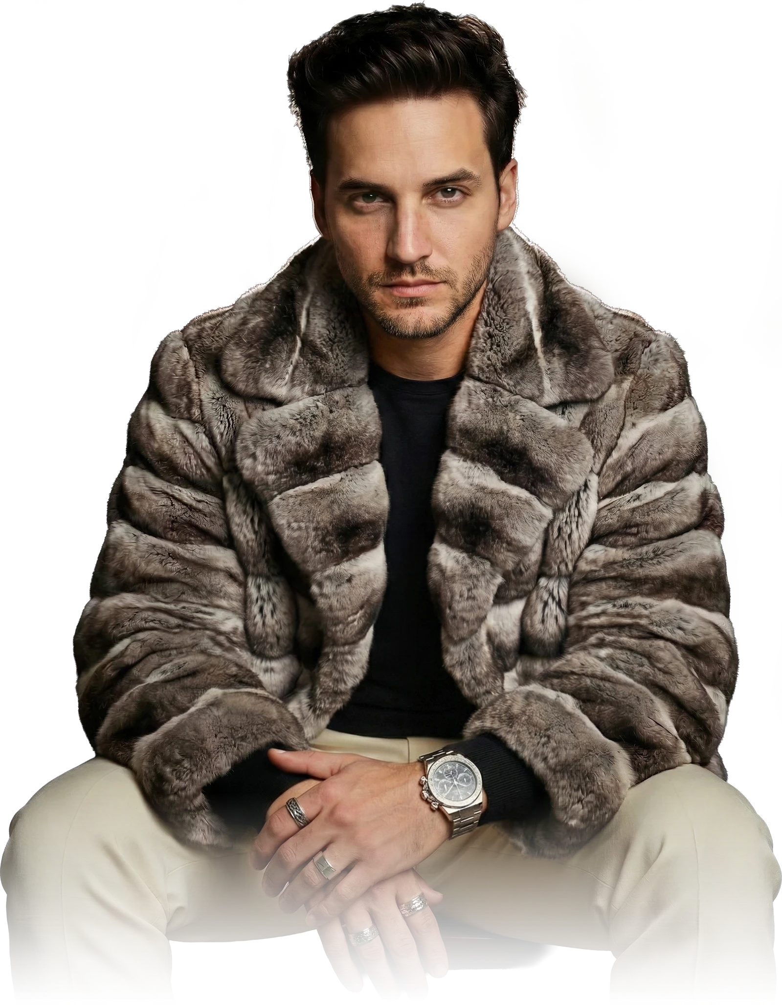 Danny Wave seated in a grey textured coat and cream trousers, on a transparent background.